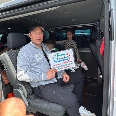 Familia con niños sosteniendo el banner de Holbox Transfers dentro de la van, ya acomodados para el trayecto a Holbox.