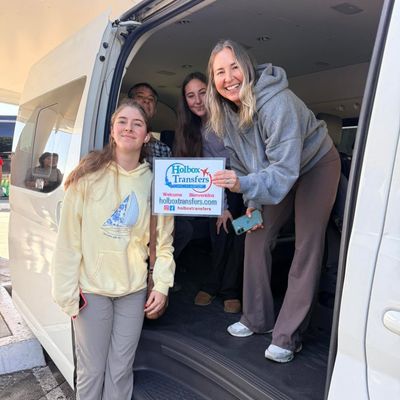 Una familia sube a la van sosteniendo junta el banner de Holbox Transfers, emocionados por comenzar el viaje a Holbox.