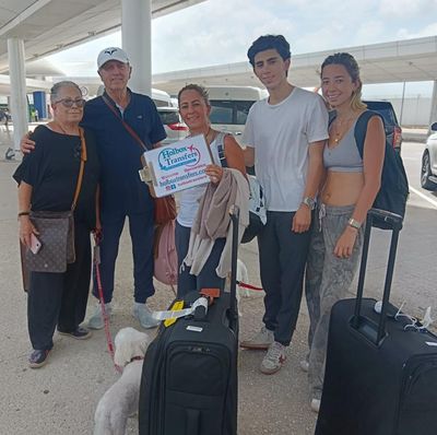 Familia con su perro de pie en la terminal, sosteniendo el banner de Holbox Transfers antes de salir hacia Holbox.
