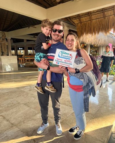Familia se abraza en el lobby de su destino en Holbox, sosteniendo con orgullo el banner de Holbox Transfers tras su traslado Aeropuerto de Cancún - Holbox.