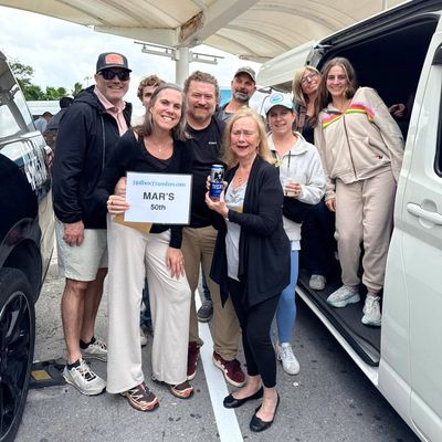 Familia y amigos sonríen juntos en la terminal, sosteniendo el banner de Holbox Transfers al comenzar su travesía a Holbox.