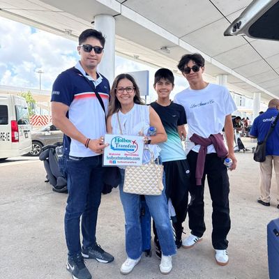 Una familia se reúne alrededor del banner de Holbox Transfers afuera de la terminal, lista para viajar de Cancún a Holbox.