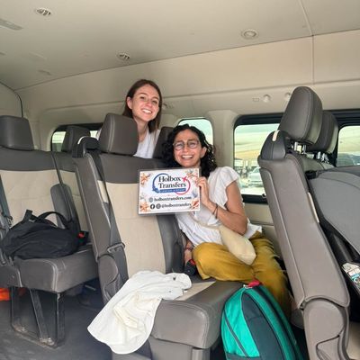 Una familia sostiene el banner de Holbox Transfers dentro de la van, ambos sonriendo mientras viajan juntos rumbo a Holbox.