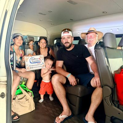 Una familia sostiene el banner de Holbox Transfers dentro de la van, un pequeño y los abuelos listos para Holbox.