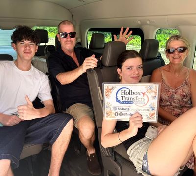Una familia sostiene el banner de Holbox Transfers dentro de la van, saludando alegremente en su camino a Holbox.