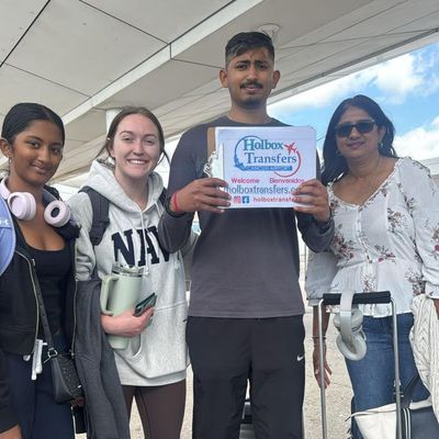 Una familia sostiene junta el banner de Holbox Transfers en la terminal del aeropuerto, lista para su travesía Aeropuerto de Cancún - Holbox.