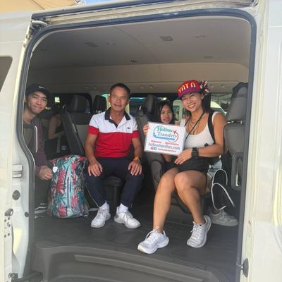 Familia sostiene junta el banner de Holbox Transfers dentro de la van, sonriendo en ruta de Puerto Juárez al Aeropuerto de Cancún.