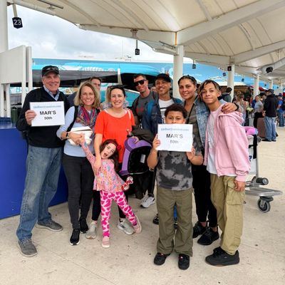Familia posa con su equipaje en la terminal, sosteniendo el banner de Holbox Transfers mientras esperan su traslado a Holbox.