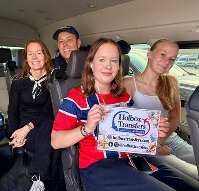Familia sentada junta en la van, una de las hijas sostiene el banner de Holbox Transfers camino a Holbox.