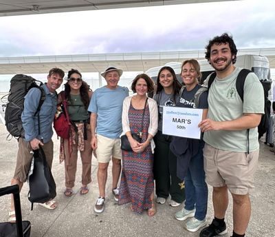 Familia sonríe junto a la puerta abierta de la van, sosteniendo el banner de Holbox Transfers al inicio de su viaje a Holbox.