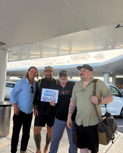 Grupo de amigos reunido alrededor del banner de Holbox Transfers en la terminal del aeropuerto en la ruta Aeropuerto de Cancún - Holbox.