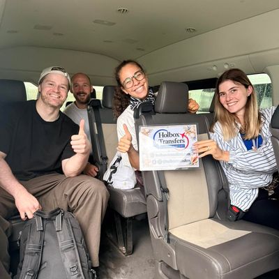 Un grupo de amigos levanta el pulgar con el banner de Holbox Transfers dentro de la van camino a Holbox.