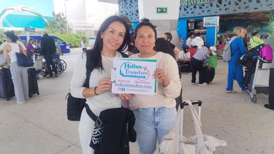 Grupo de amigos sostiene el banner de Holbox Transfers en la terminal del aeropuerto, puras sonrisas antes del traslado Aeropuerto de Cancún - Holbox.