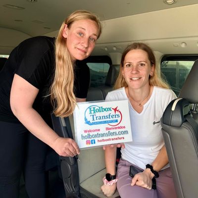 Grupo de amigos sostiene el banner de Holbox Transfers dentro de la van, sonriendo juntos en la ruta Aeropuerto de Cancún - Holbox.