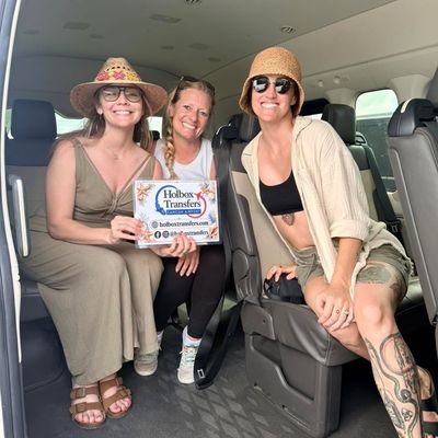 Grupo de amigos sostiene el banner de Holbox Transfers dentro de la van, riendo juntos en el trayecto Aeropuerto de Cancún - Holbox.