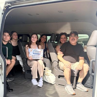 Un grupo de amigos sostiene el banner de Holbox Transfers dentro de la van, todos sonriendo juntos camino a Holbox.