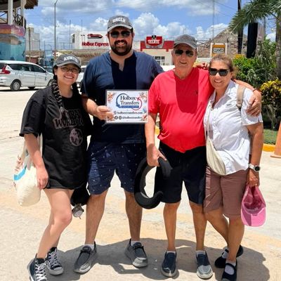 Un grupo de amigos sostiene el banner de Holbox Transfers en una calle soleada de Holbox, cerrando juntos su viaje.