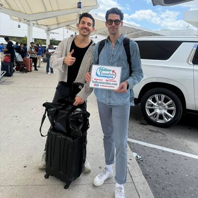 Un grupo de amigos ríe sosteniendo el banner de Holbox Transfers en la terminal del aeropuerto, listos para su viaje a Holbox.