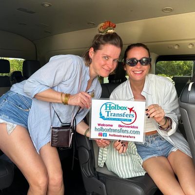 Grupo de amigos se acerca dentro de la van, sosteniendo el banner de Holbox Transfers durante su trayecto rumbo a Holbox.