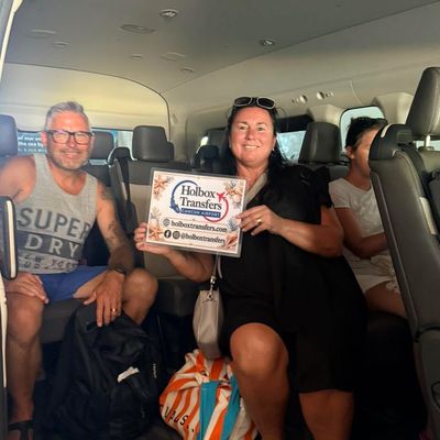 Grupo de amigos viajando en la van, uno sostiene el banner de Holbox Transfers mientras se dirigen rumbo a Holbox.