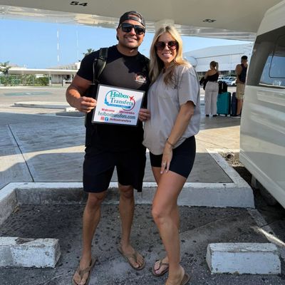 Un grupo de amigos de pie sostiene el banner de Holbox Transfers en la terminal del aeropuerto antes de su viaje a Holbox.