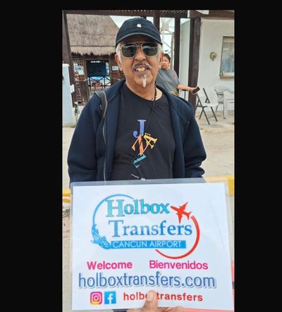 Viajero solo sonríe sosteniendo el banner de Holbox Transfers cerca de la terminal del ferry camino a Holbox.